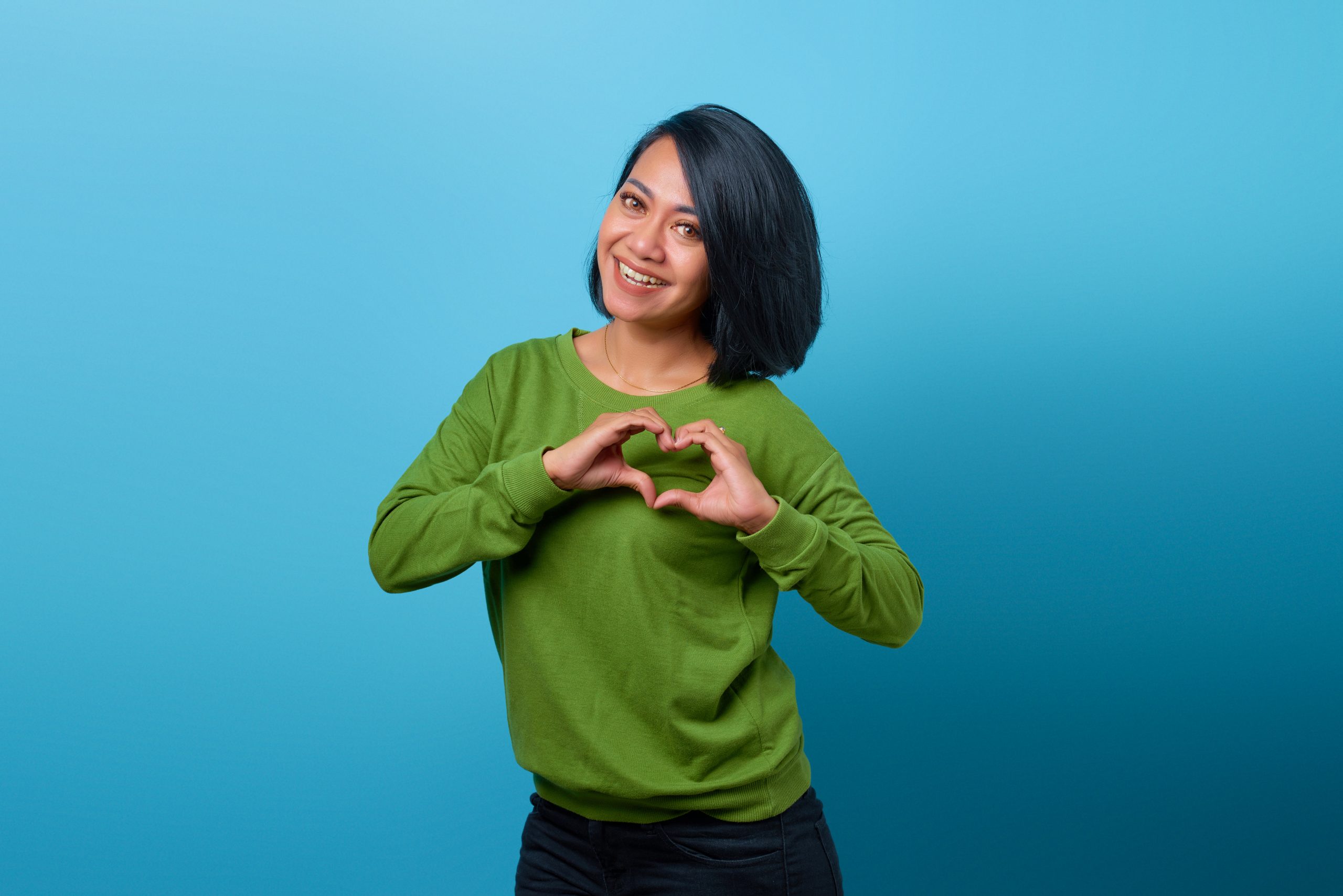 Portrait,Of,Smiling,Asian,Woman,Showing,Heart,Gesture,With,Two